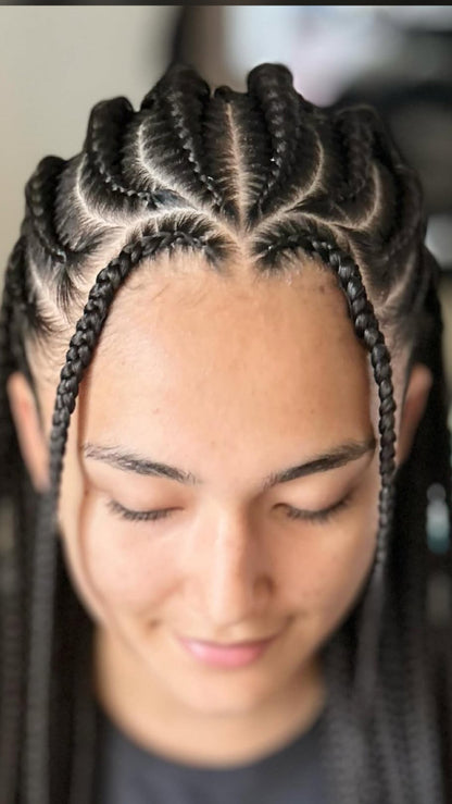 Close-up of a person with intricate braided fulani braids with hair extensions styled in a geometric cornrow pattern, looking down with eyes closed.