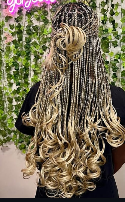 Long waist length wavy french curl braids with blonde and dark brown highlights, styled in a half-up bun with a headband, shown from the back on a model.