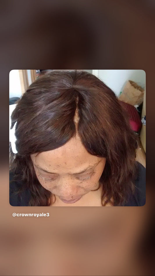 A close-up view of a person with shoulder-length dark brown hair, looking downward. She wears an invisible part weave The photo is framed with a rounded white border, set against a blurred brown background, with the handle @crownroyale3 visible in the lower-left corner.
