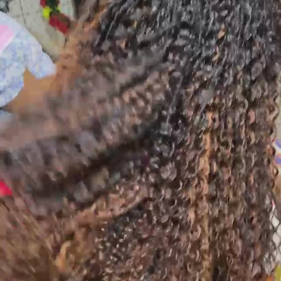 video showing sariette tichaa founder of crown royale hair getting her hair done in kinky curly mid back length boho braids dyed to an ombre caramel brown hair color using the crown royale hair human hair line