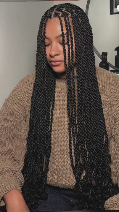 woman wearing waist length senegalese twist with curled ends she has her eyes closed and facelooking downwards