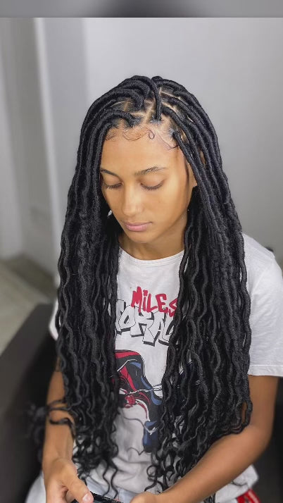 ladu with individual faux locs wearing a white t shirt and looking down ward